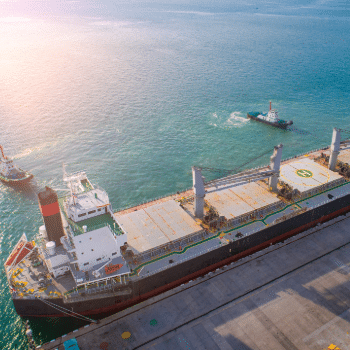 cargo ship and tugboats at an international port, representing the global supply chain pressures and trade routes affected by ongoing electronics and semiconductor tariffs