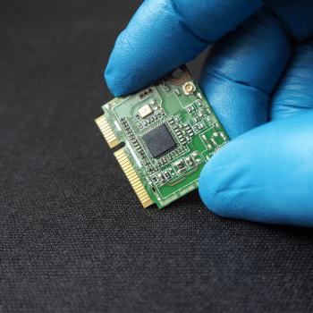 industrial PC expansion card held by a technician wearing blue gloves for embedded computer connectivity and industrial automation systems